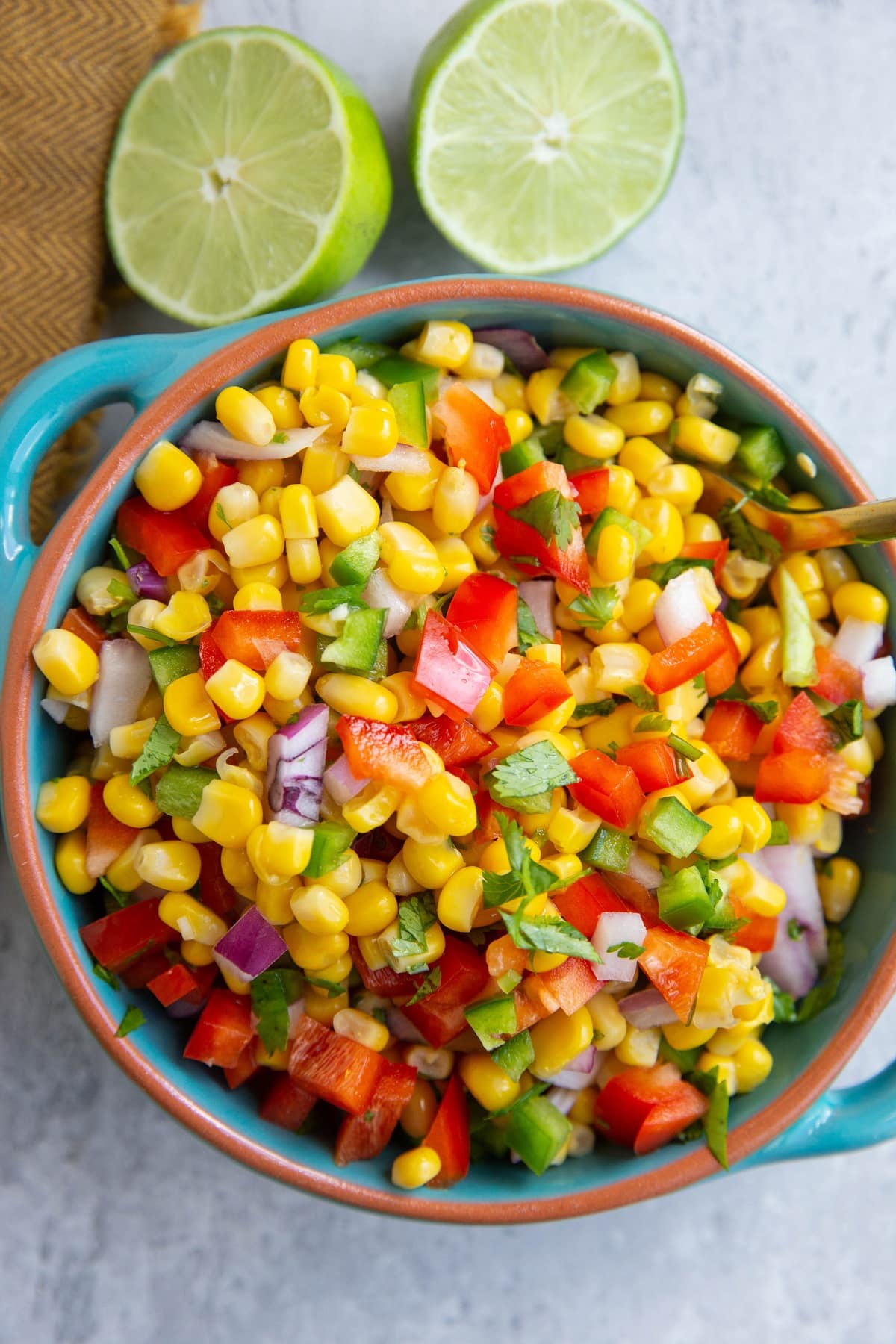 Blue bowl full of corn salsa with a cut fresh lime to the side.