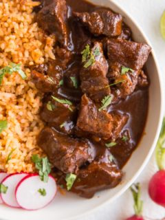 Chile Colorado in a white bowl with Mexican rice for the perfect meal.