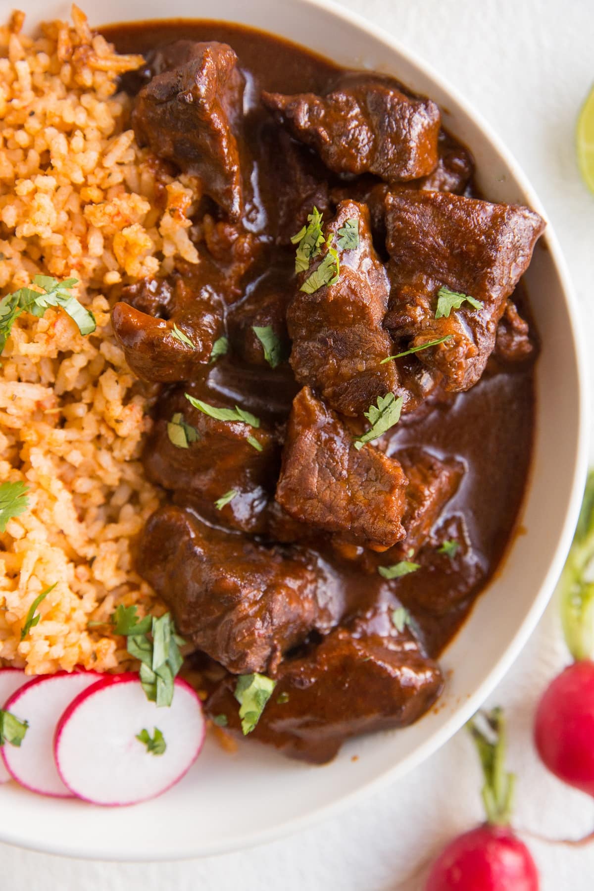 Chile Colorado in a white bowl with Mexican rice for the perfect meal.