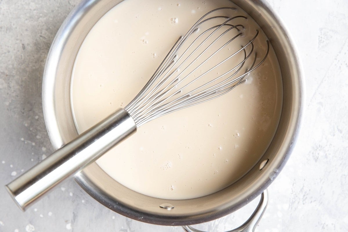 Creamy ice cream base in a saucepan with a whisk