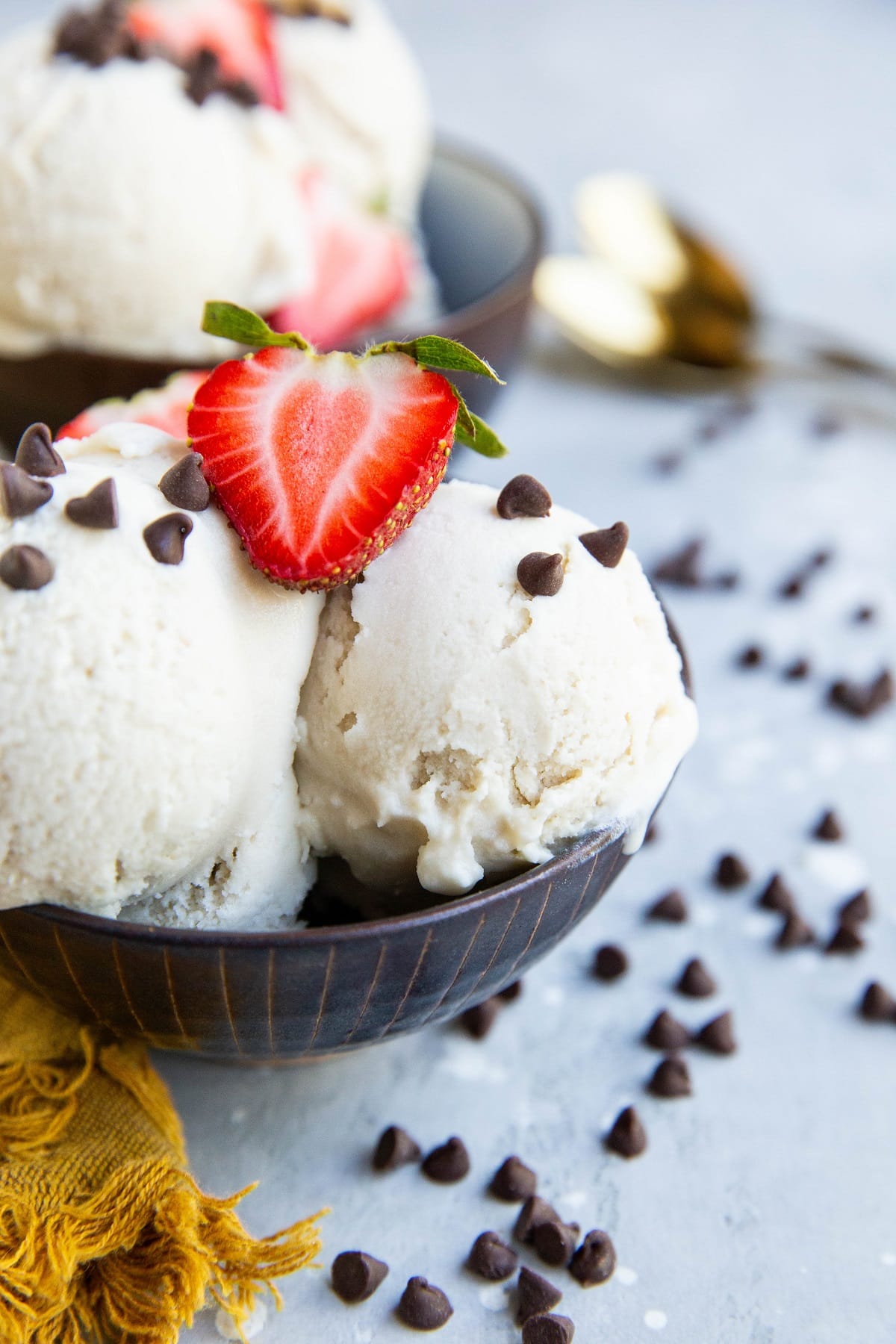 Two bowls of scoops of vanilla ice cream with mini chocolate chips and berries on top. Ready to eat.