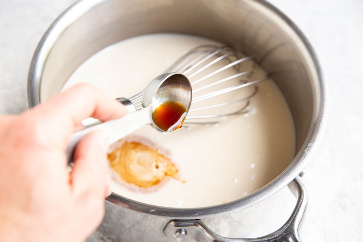 Pouring a tablespoon of vanilla extract into the saucepan