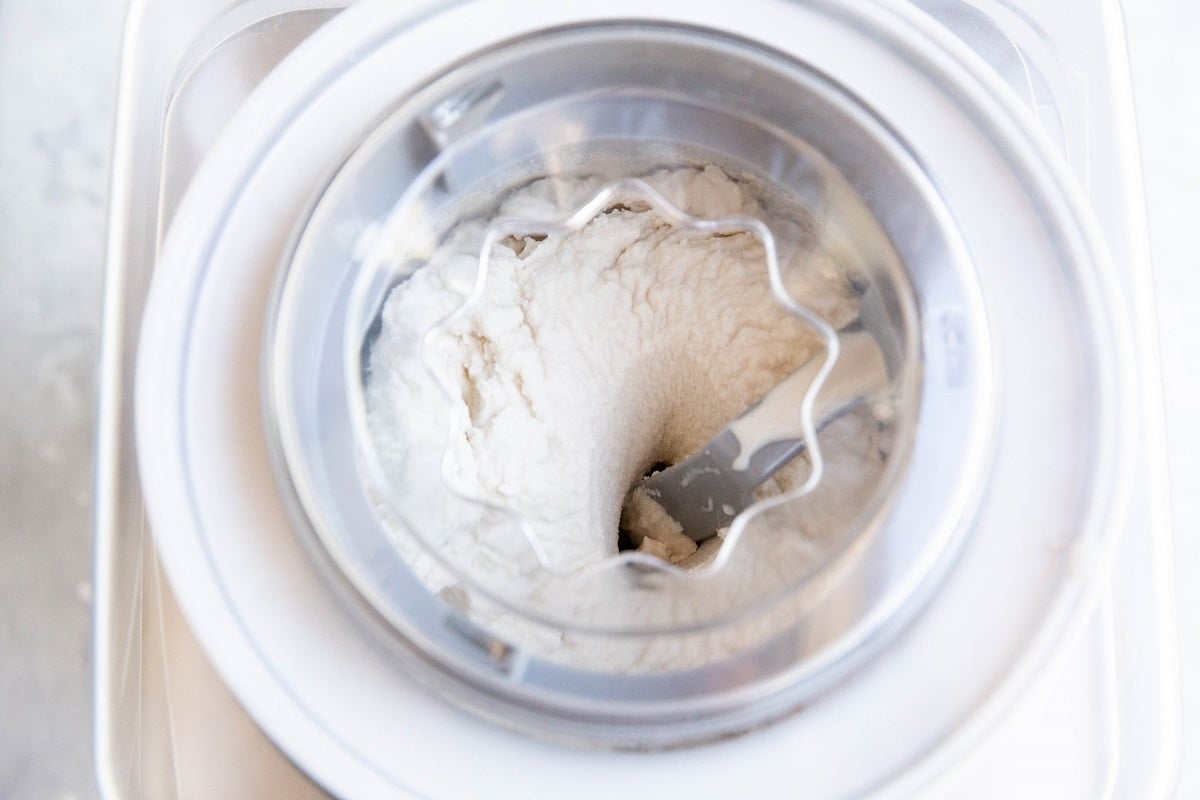 Ice cream machine with vanilla ice cream churning in it.