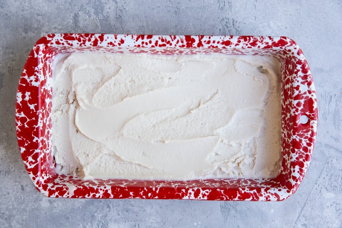 Red loaf pan full of vanilla ice cream.