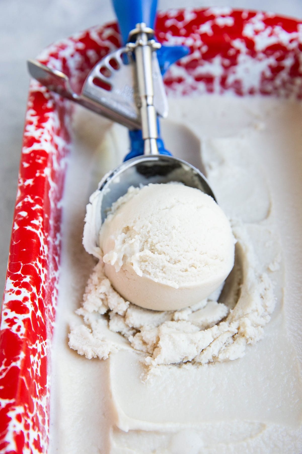 Homemade vanilla ice cream with an ice cream scoop scooping one scoop out.