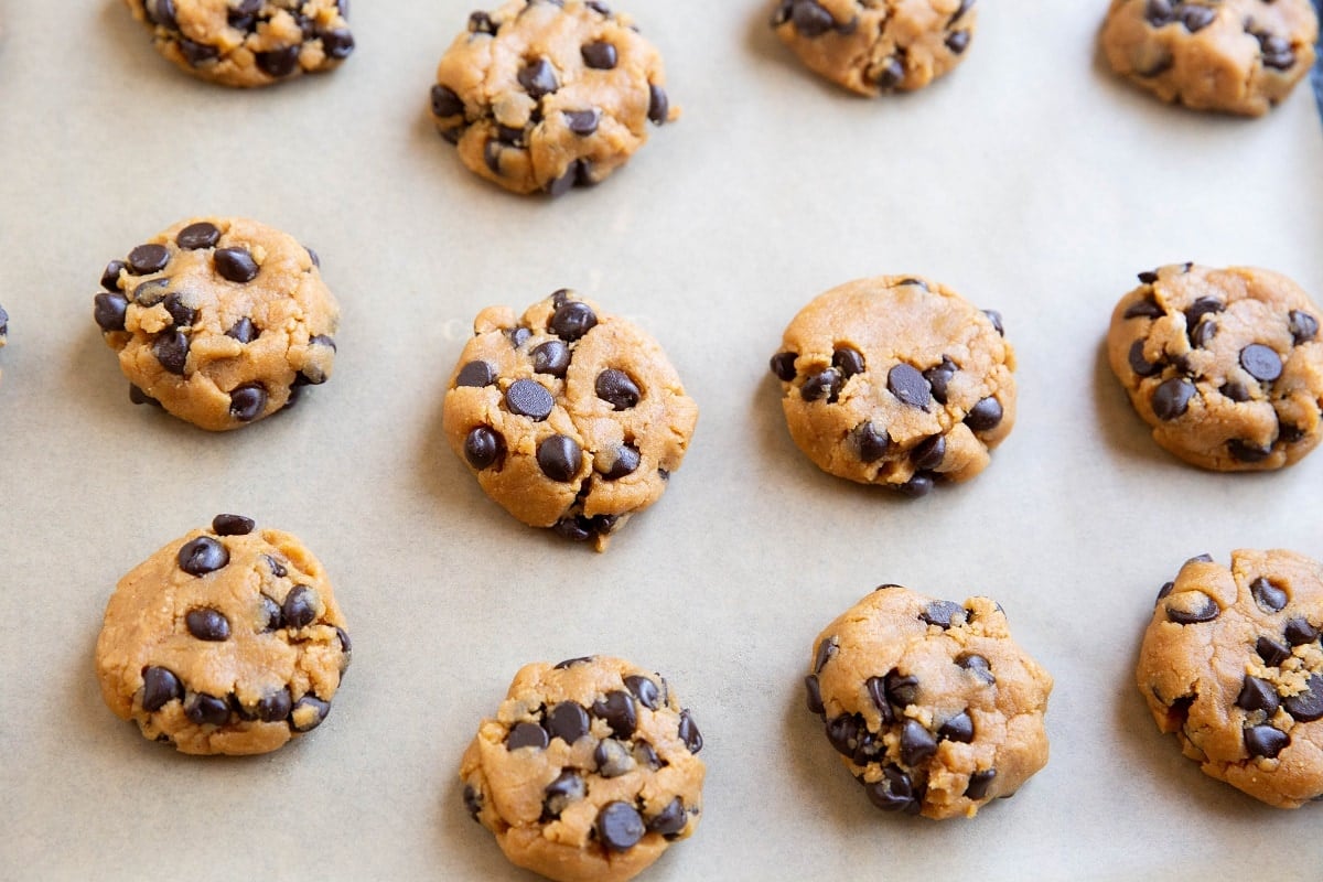 Discs of peanut butter cookie dough on a baking sheet, ready to be baked.