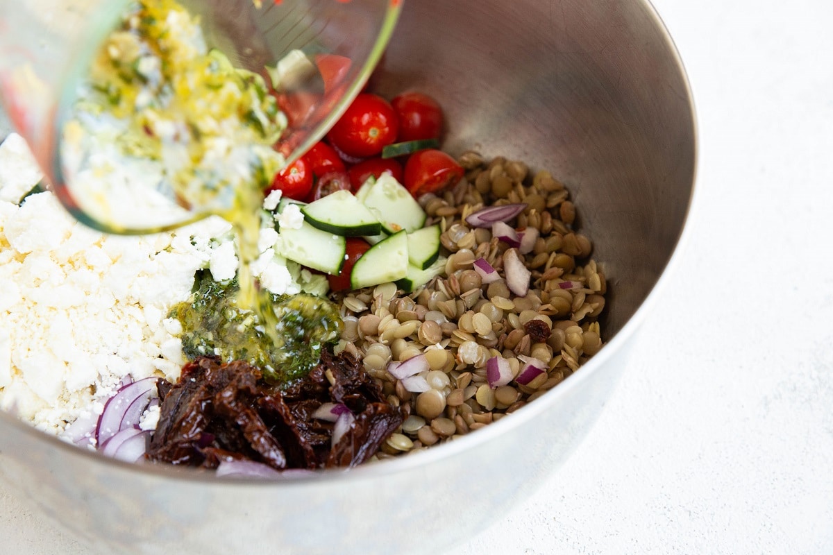 Pouring the salad dressing into the mixing bowl with salad ingredients.