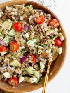 Big bowl of lentil salad with a golden spoon.