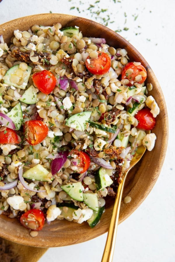 Big bowl of lentil salad with a golden spoon.