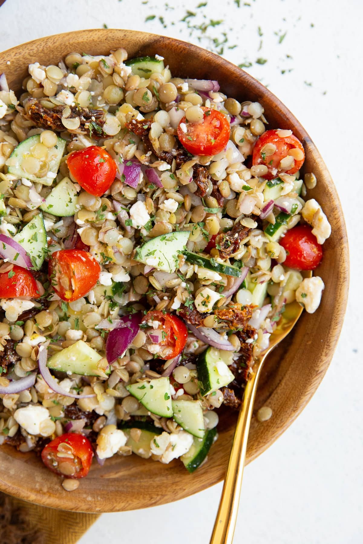 Big bowl of lentil salad with a golden spoon.