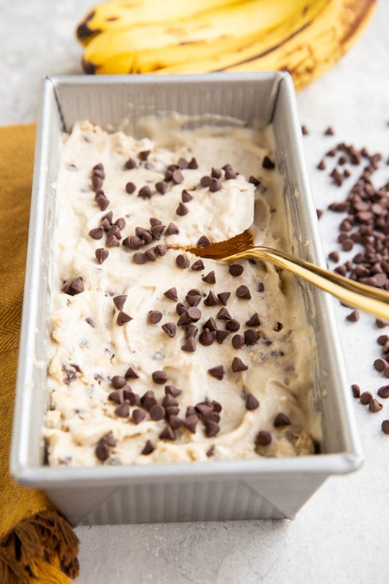 Container of cookie dough ice cream with chocolate chips all around.