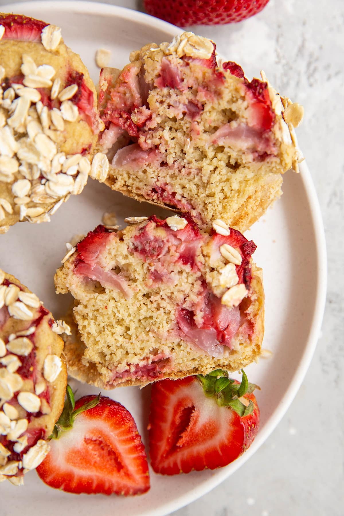 Muffin cut in half on a white plate with other muffins.