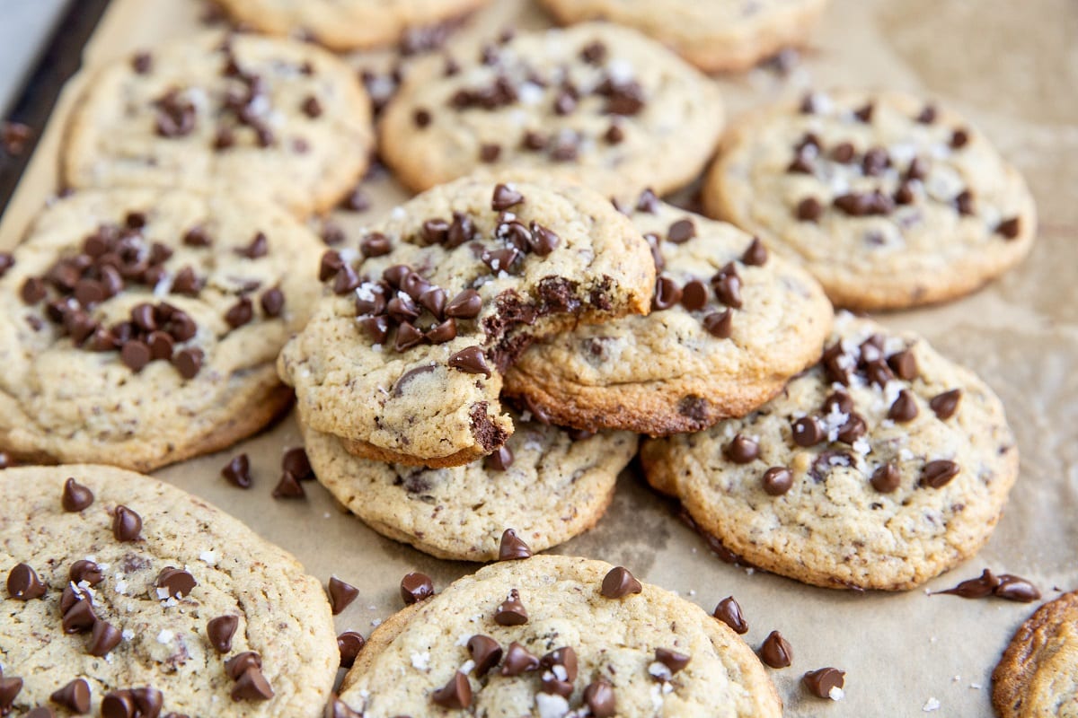 Pile of cookies on a cookie sheet, with a bite taken out of one of them.