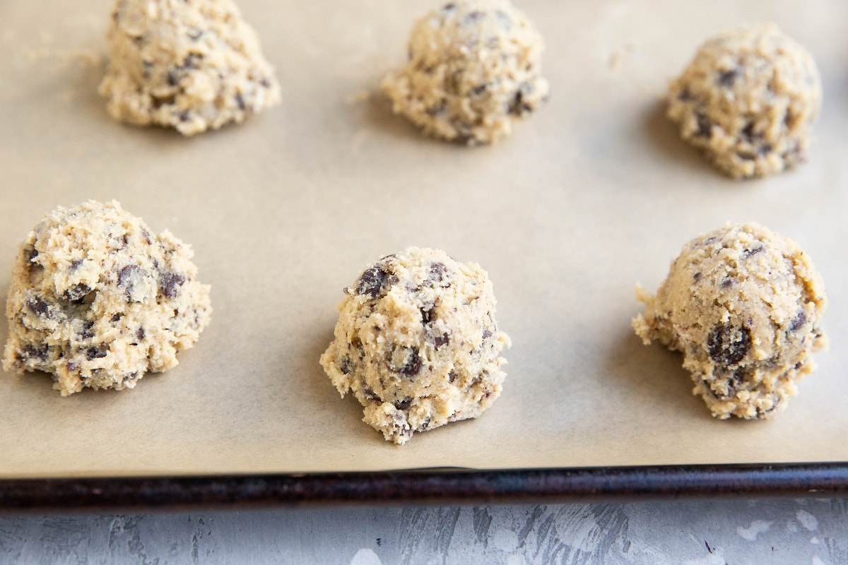 Cookie dough balls on a prepared cookie sheet.