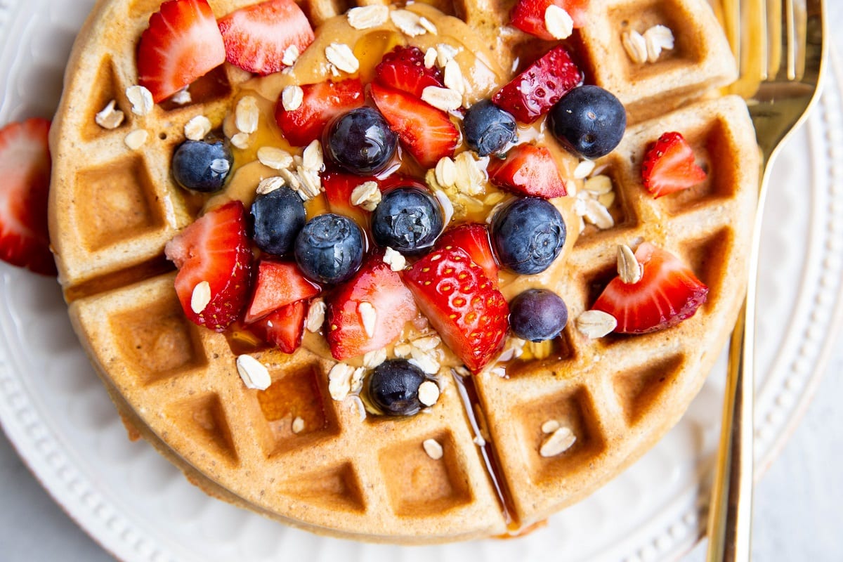 Close up horizontal photo of waffles on a plate with fresh berries.