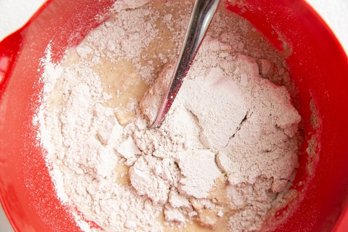 Wet ingredients in a mixing bowl with dry ingredients on top, ready to be mixed in.