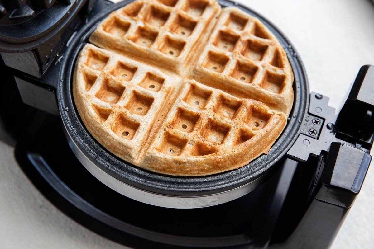 Belgian waffle maker with a freshly made waffle inside.