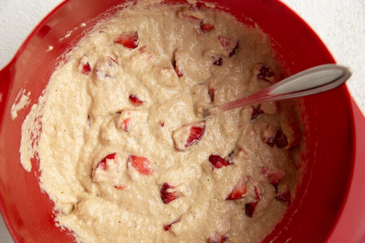 Strawberry muffin batter in a red mixing bowl.
