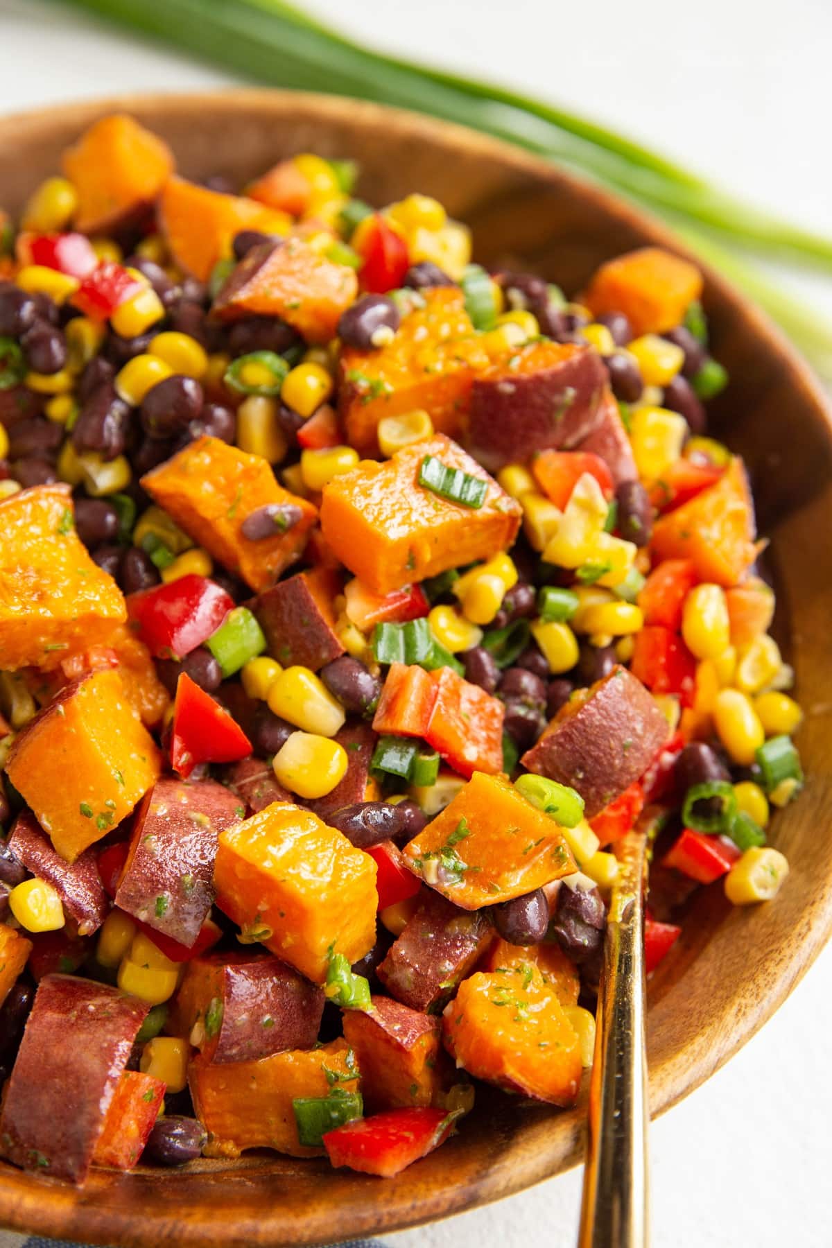Close up image of a serving bowl full of roasted sweet potato salad with black beans, corn, and more.
