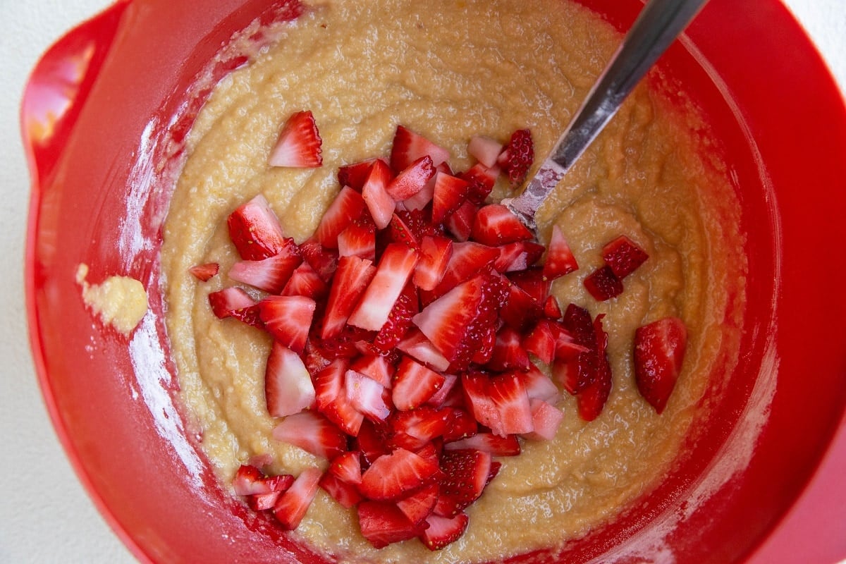 Fresh chopped strawberries on top of muffin batter, ready to be mixed in.