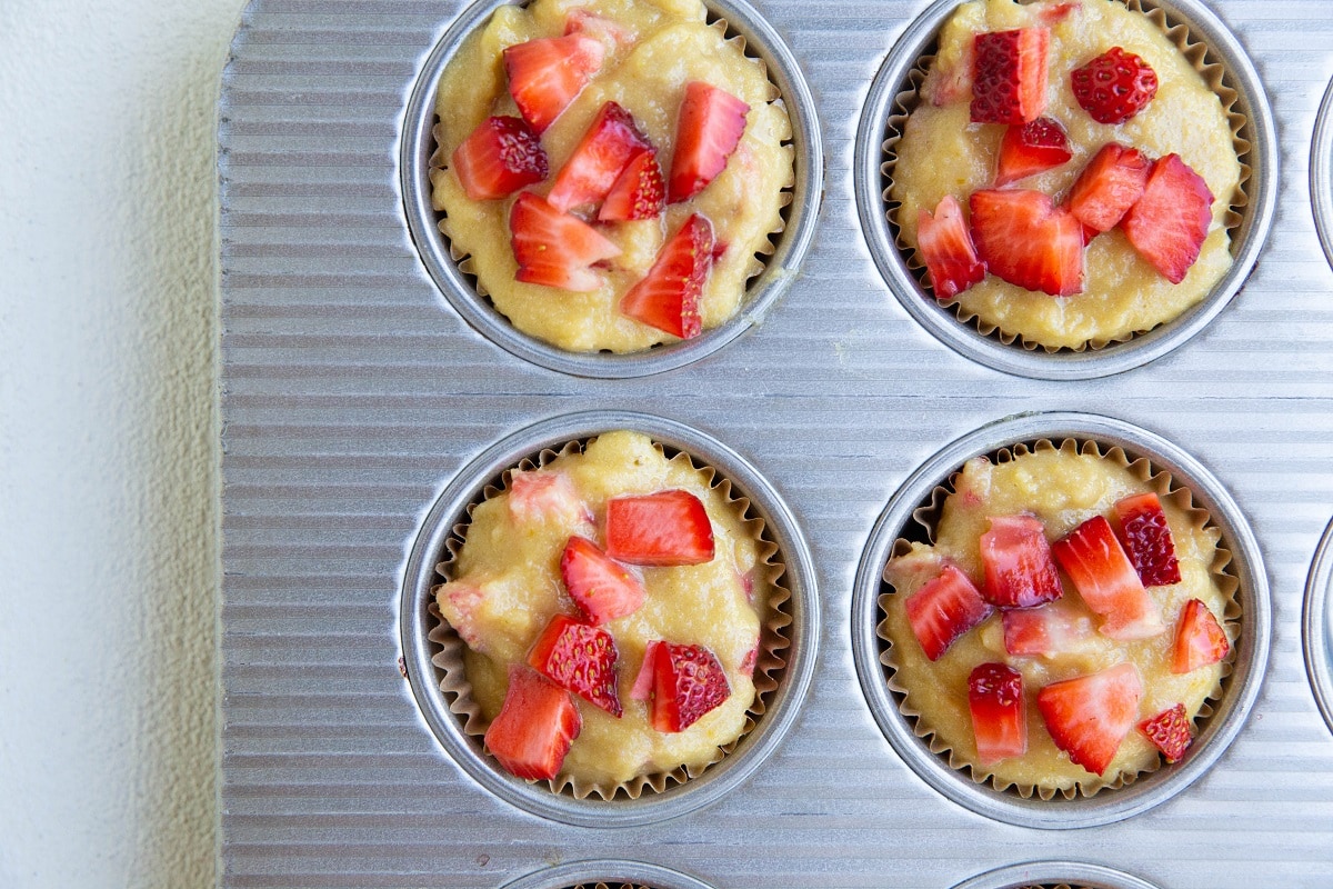 Muffin tray with muffin batter inside, ready to bake.