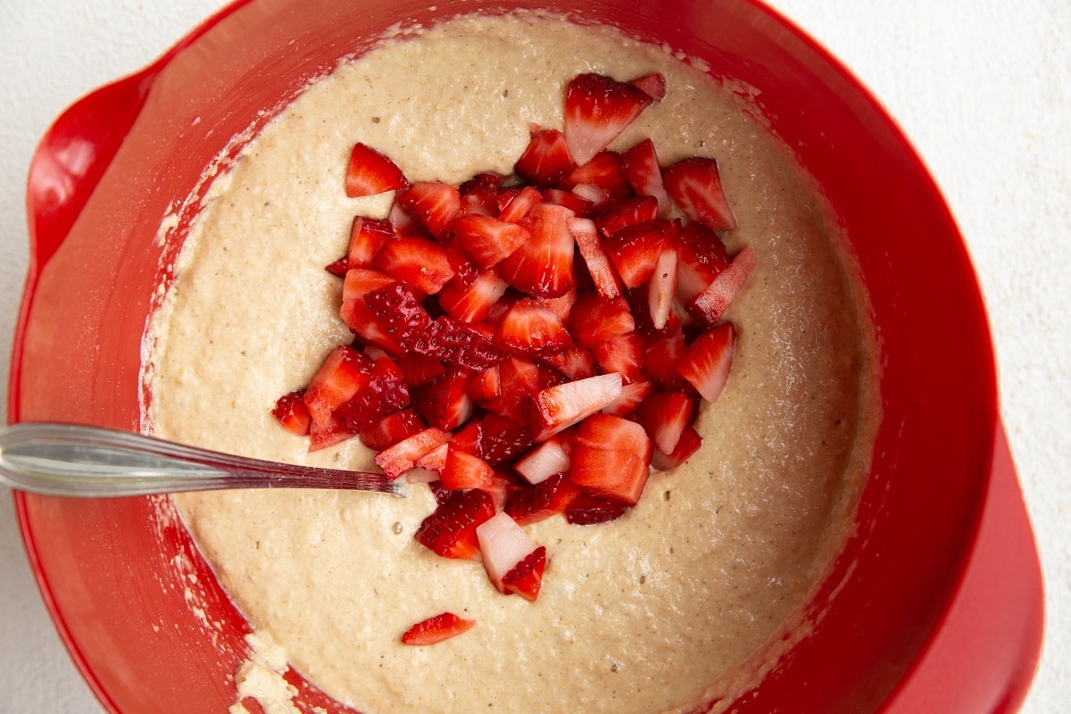 Strawberries on top of muffin batter, ready to be mixed in.