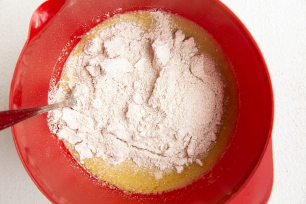 Wet ingredients in a mixing bowl with dry ingredients on top.