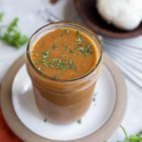 Tri Tip marinade in a jar with fresh parsley and garlic to the side.