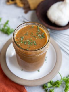 Tri Tip marinade in a jar with fresh parsley and garlic to the side.