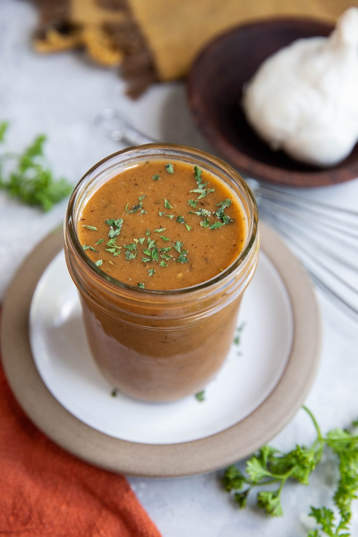 Tri Tip marinade in a jar with fresh parsley and garlic to the side.