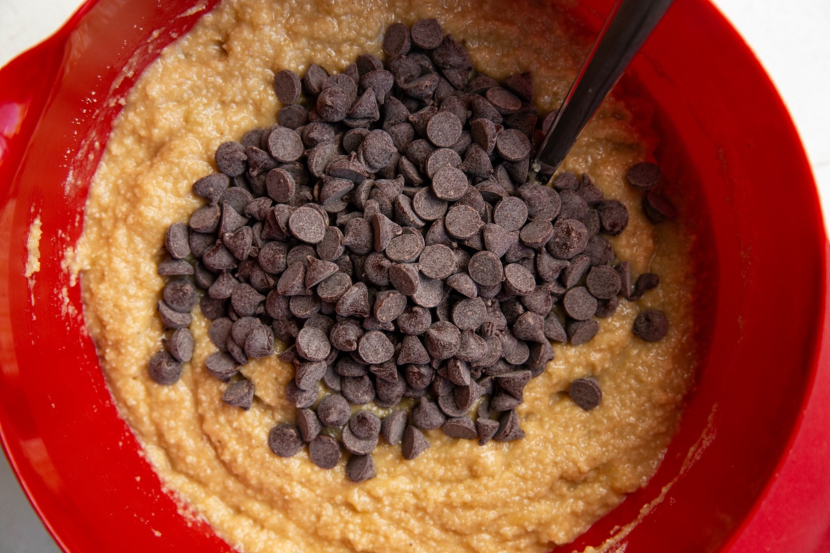 Chocolate chips on top of banana bread batter in a mixing bowl.
