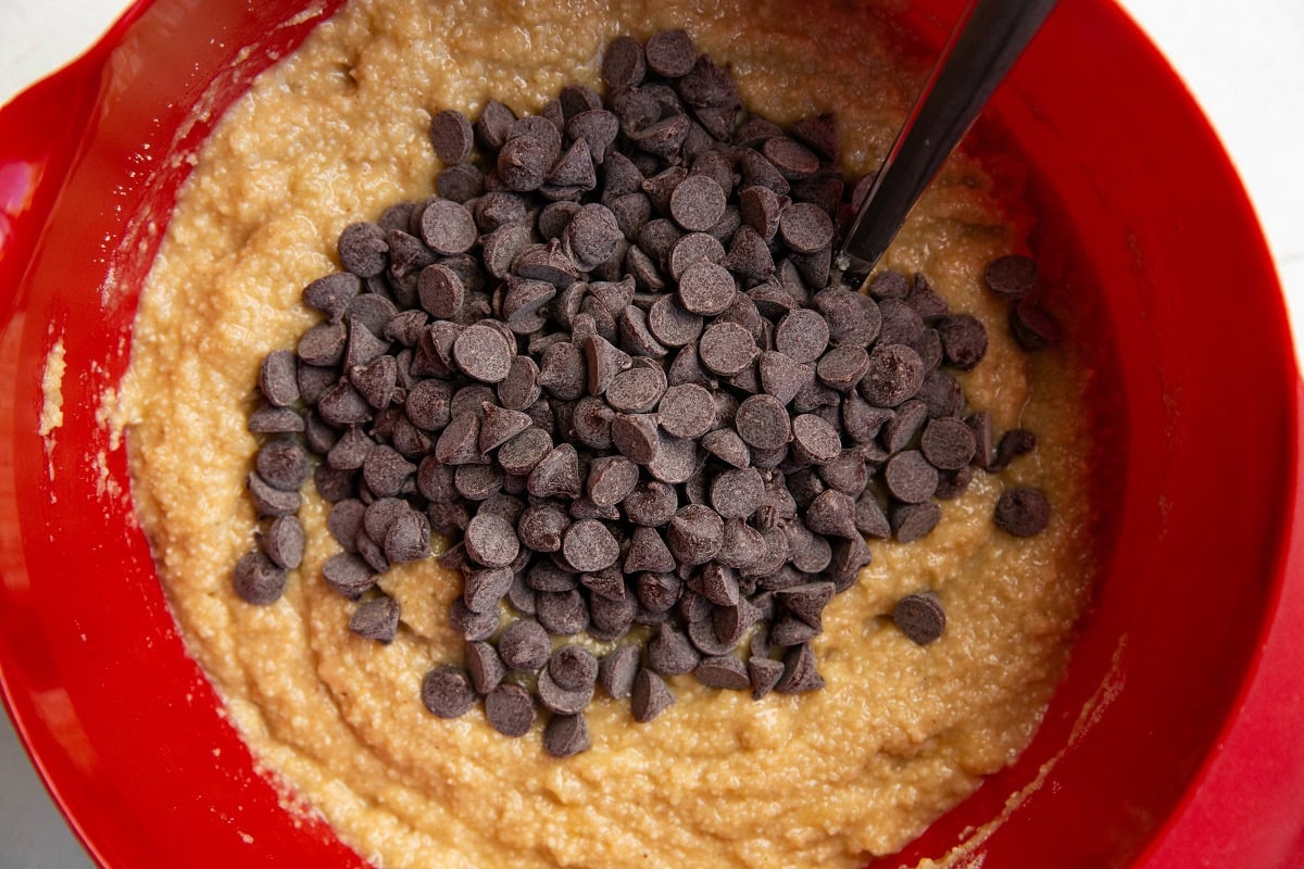 Chocolate chips on top of banana bread batter in a mixing bowl.