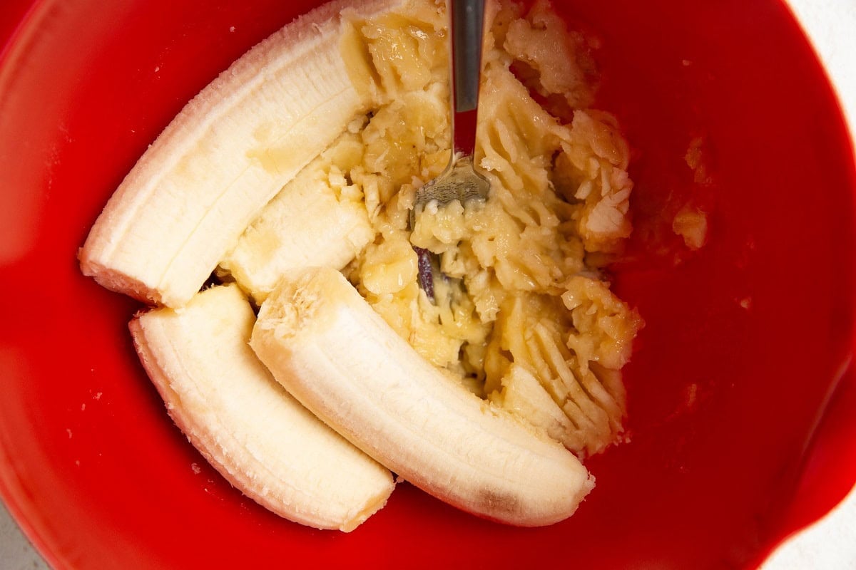 Mashed bananas in a red mixing bowl.