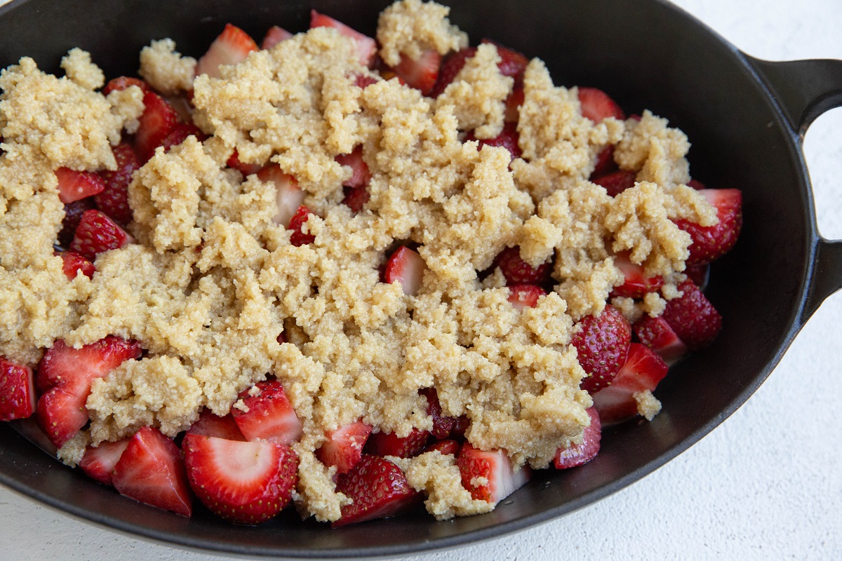 Almond flour strawberry crumble in a baking dish, ready to go into the oven.