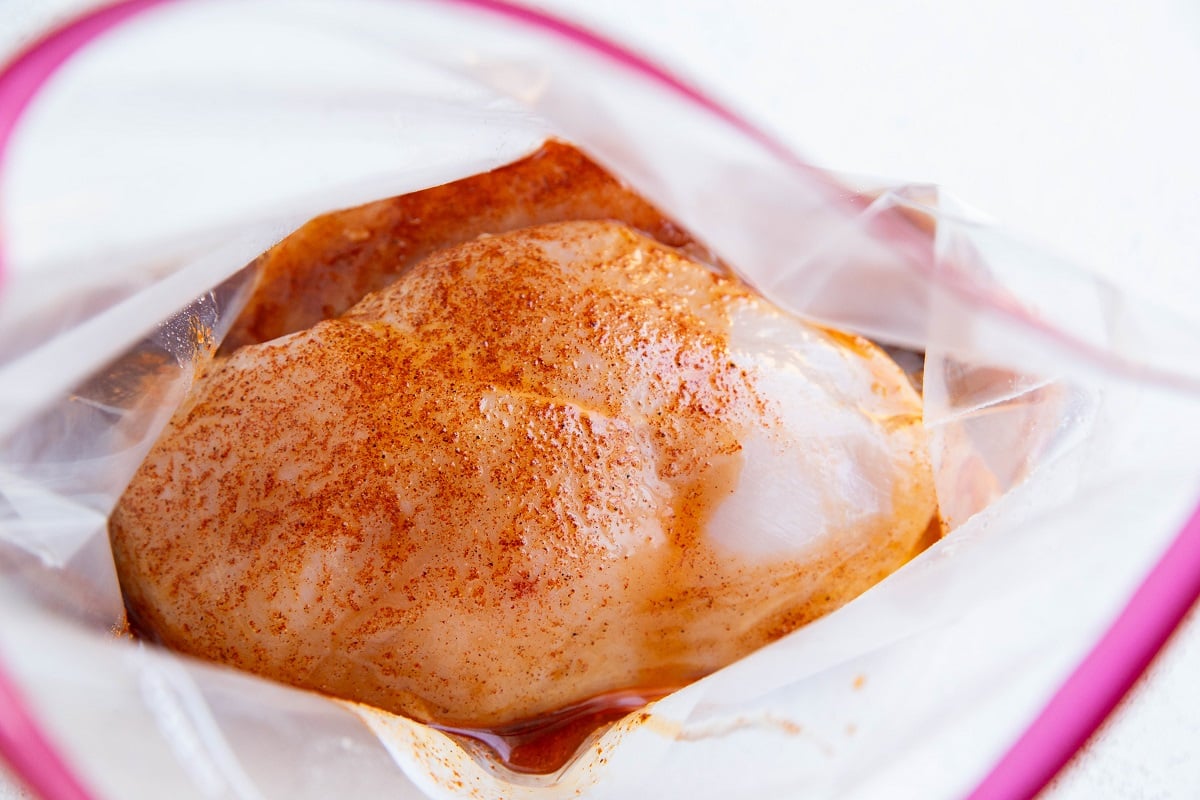 Raw boneless chicken breasts in a plastic zip lock bag with the chili lime marinade.