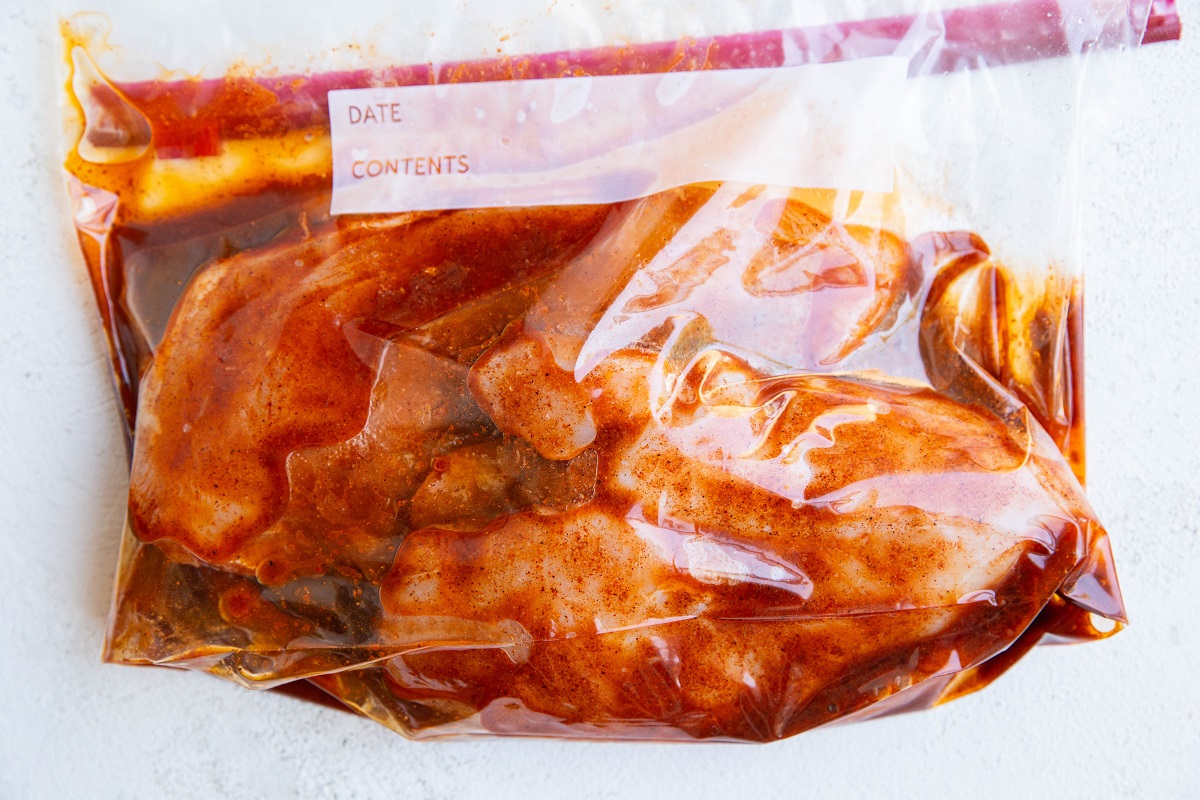 Large freezer bag with raw chicken and marinade, ready to be refrigerated.