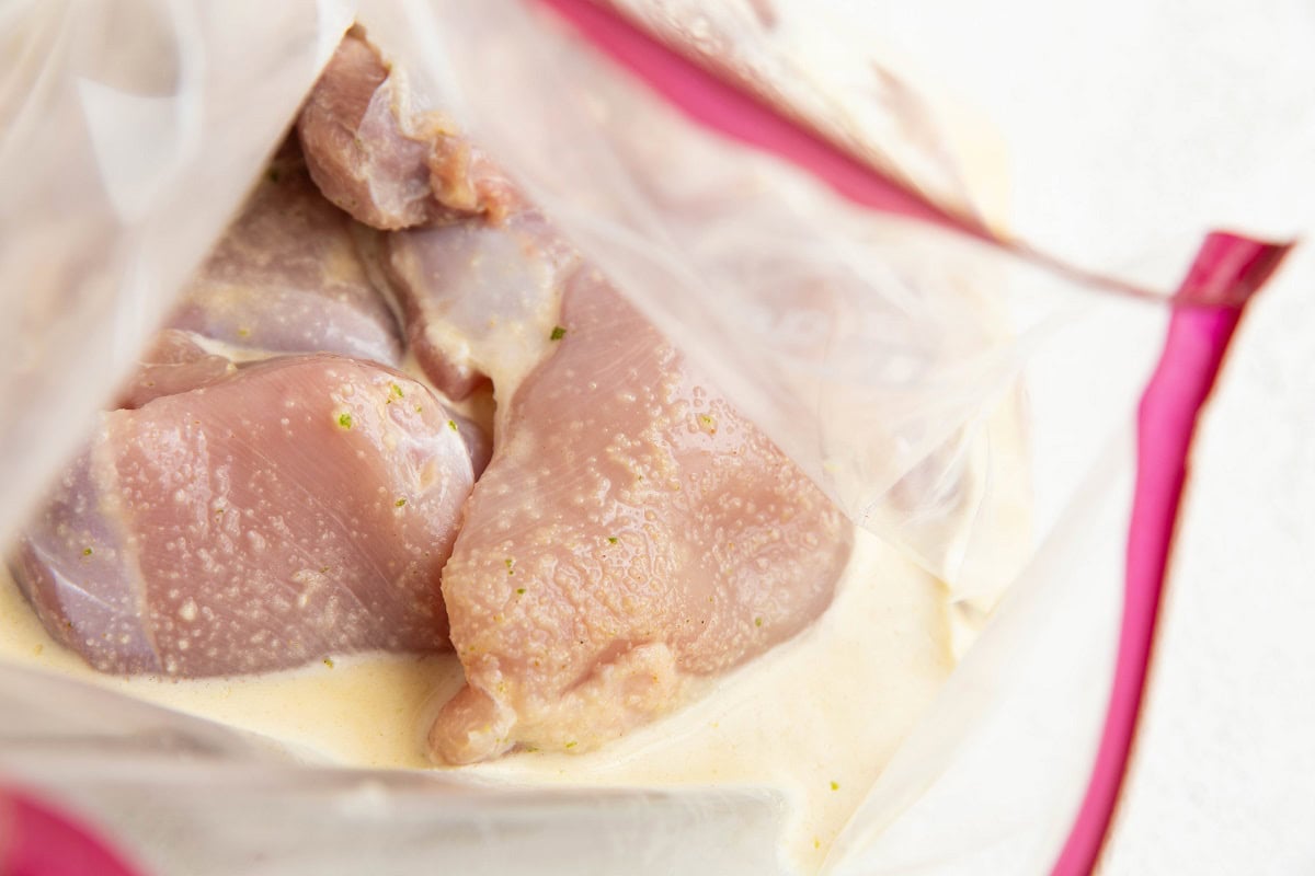 raw chicken thighs with mojo marinade in a zip lock bag.