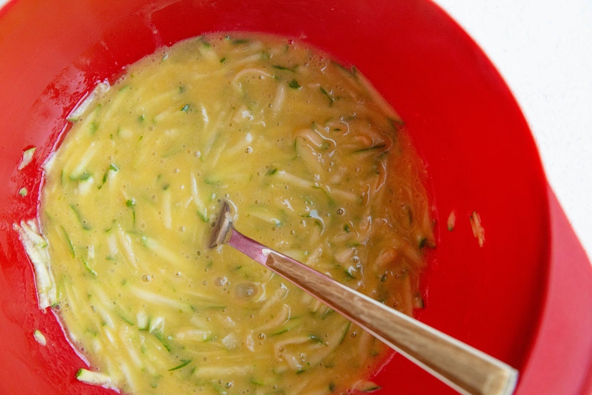 Shredded zucchini and eggs in a mixing bowl for the wet ingredients.