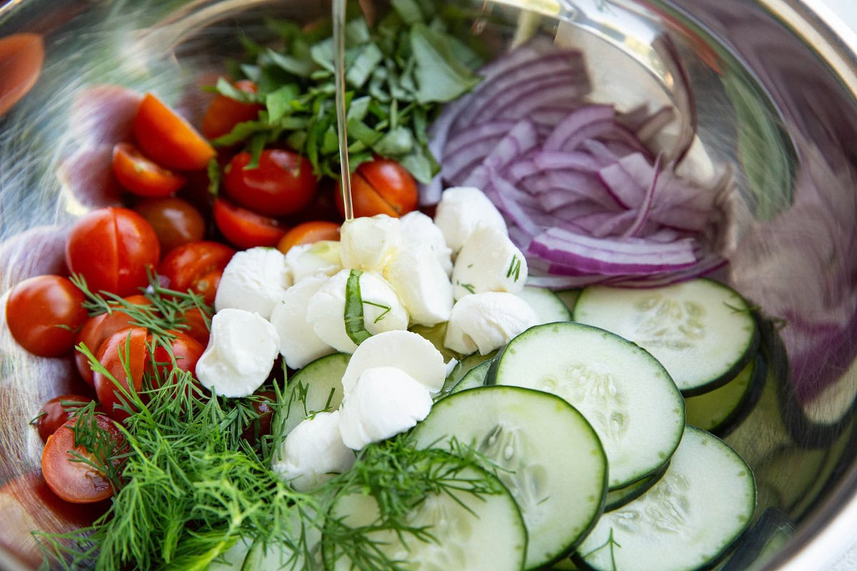 Olive oil being poured into a tomato salad.