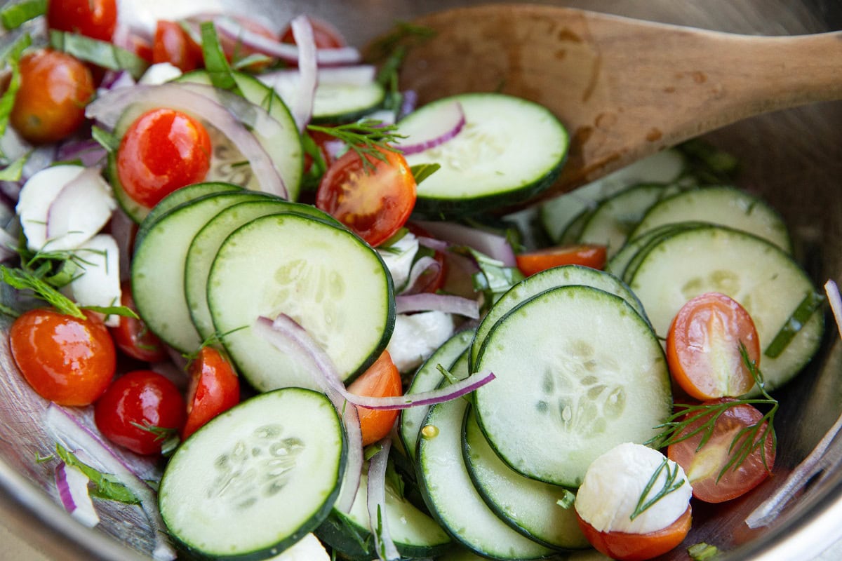 Cucumber tomato salad mixed up in a mixing bowl, ready to serve.