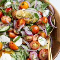 Cucumber tomato salad with balsamic vinegar drizzled on top with a gold spoon.