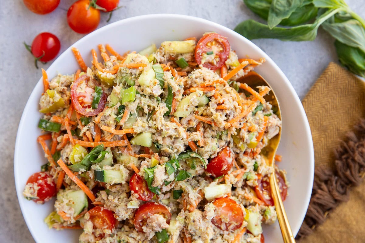 Canned salmon salad in a white bowl with fresh produce.