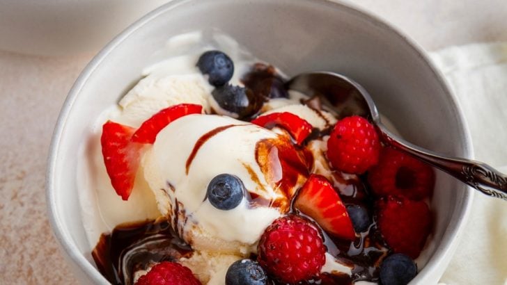 Two bowls of vanilla ice cream with fresh berries and chocolate sauce, ready to serve.