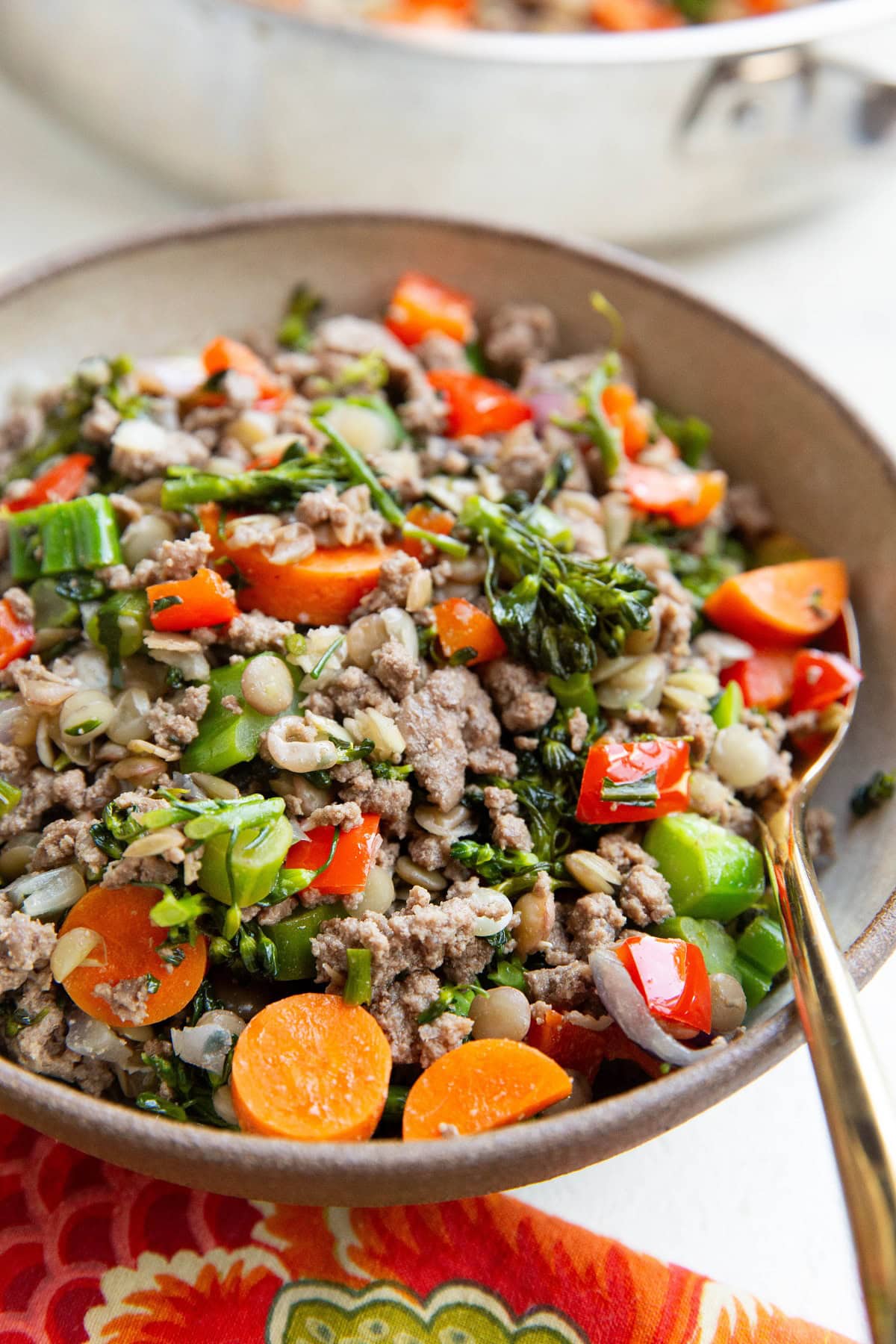 Big bowl of ground beef and veggies with a golden spoon.