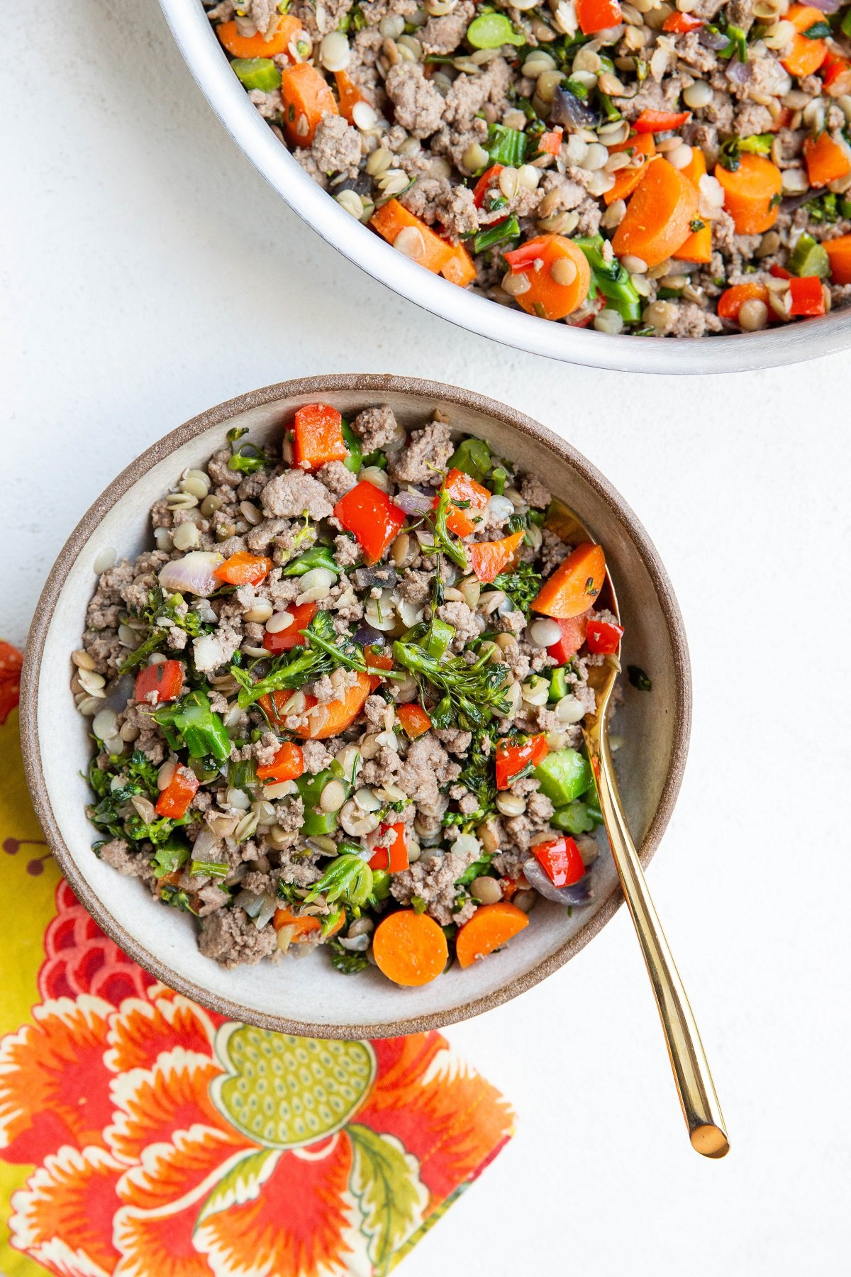 Bowl and skillet full of ground beef, lentils, and veggies.