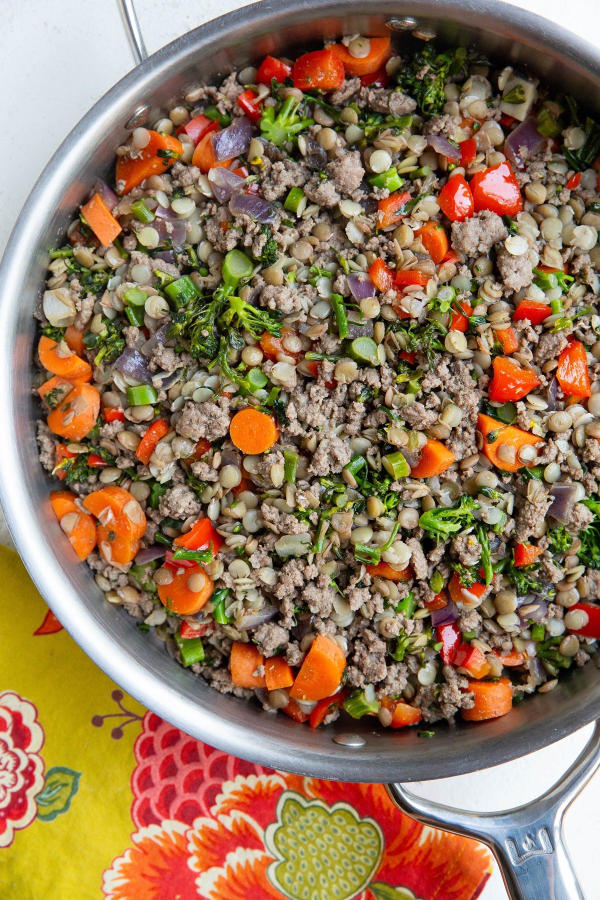 Ground beef, lentils, and vegetables in a stainless steel skillet with a napkin to the side.