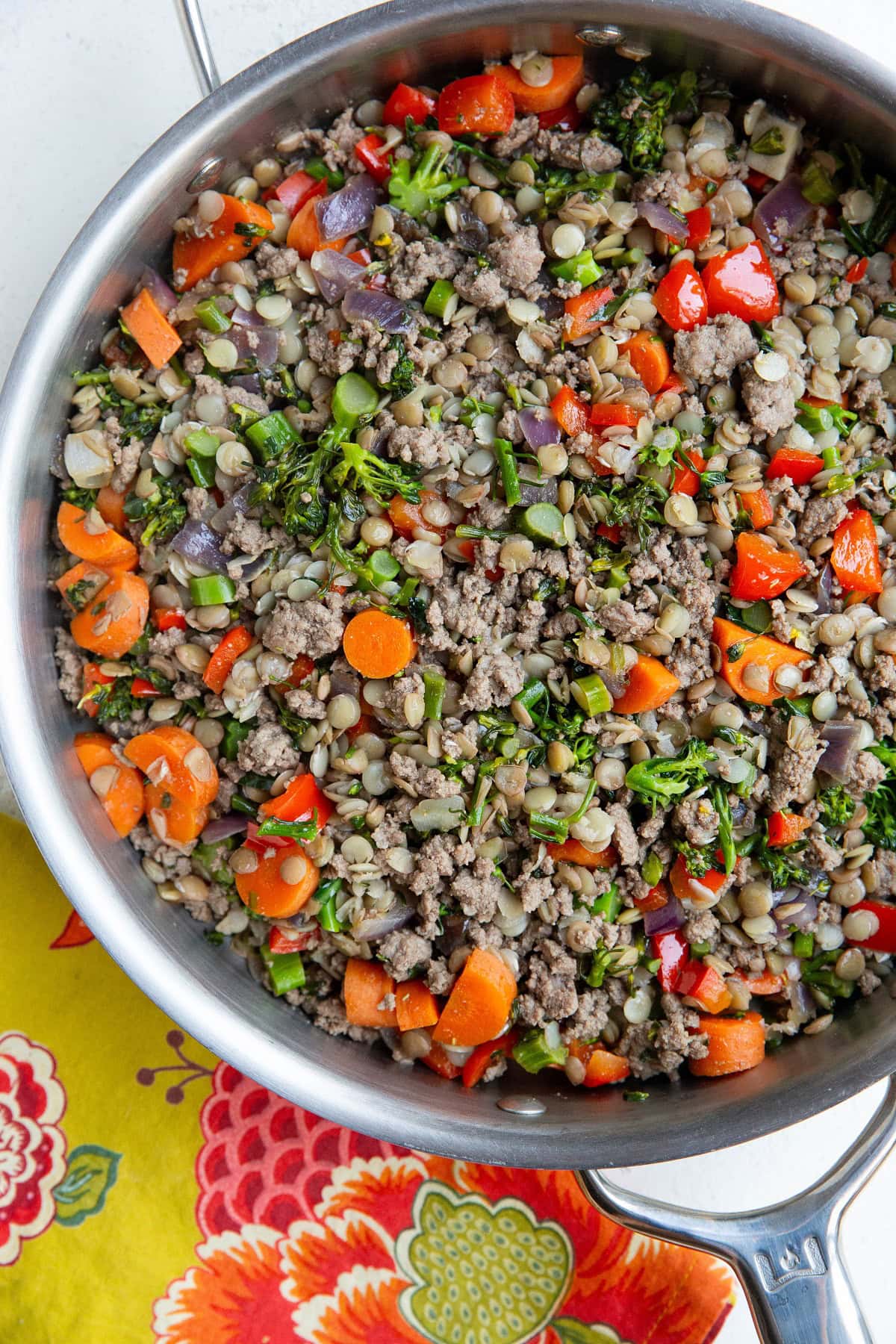 Ground beef, lentils, and vegetables in a stainless steel skillet with a napkin to the side.