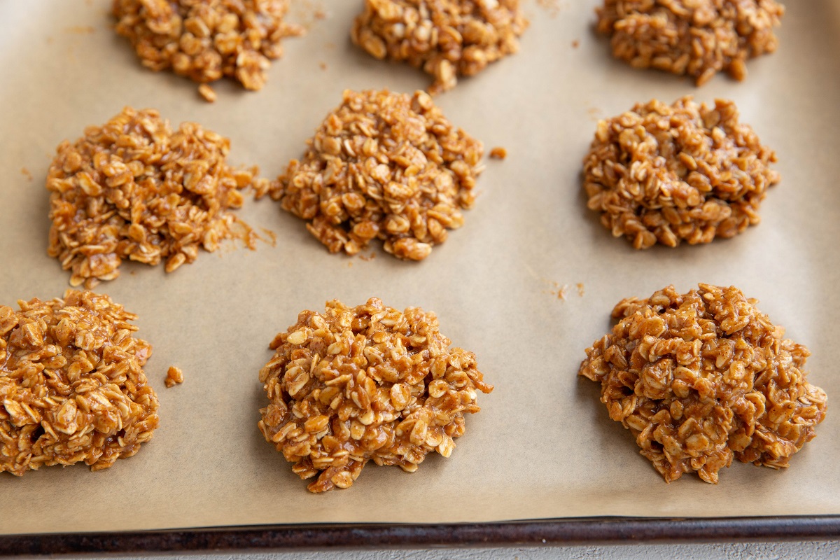Mounds of almond butter oatmeal cookie dough on a baking sheet lined with parchment paper.