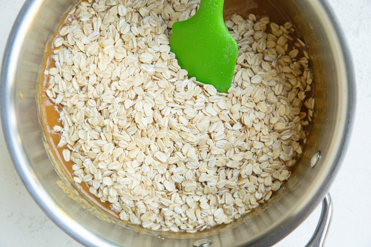 Wet ingredients for no-bake cookies with oats on top in a saucepan, ready to be mixed in.