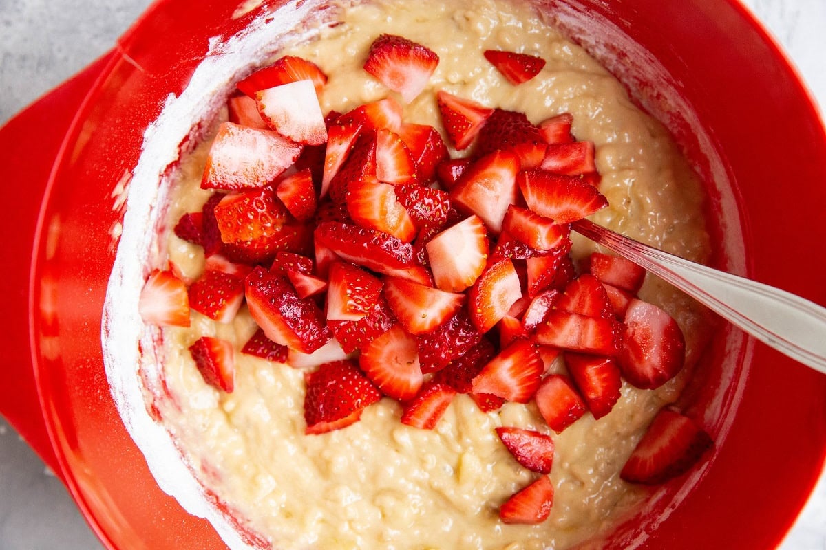 Strawberries on top of muffin batter to be mixed in.